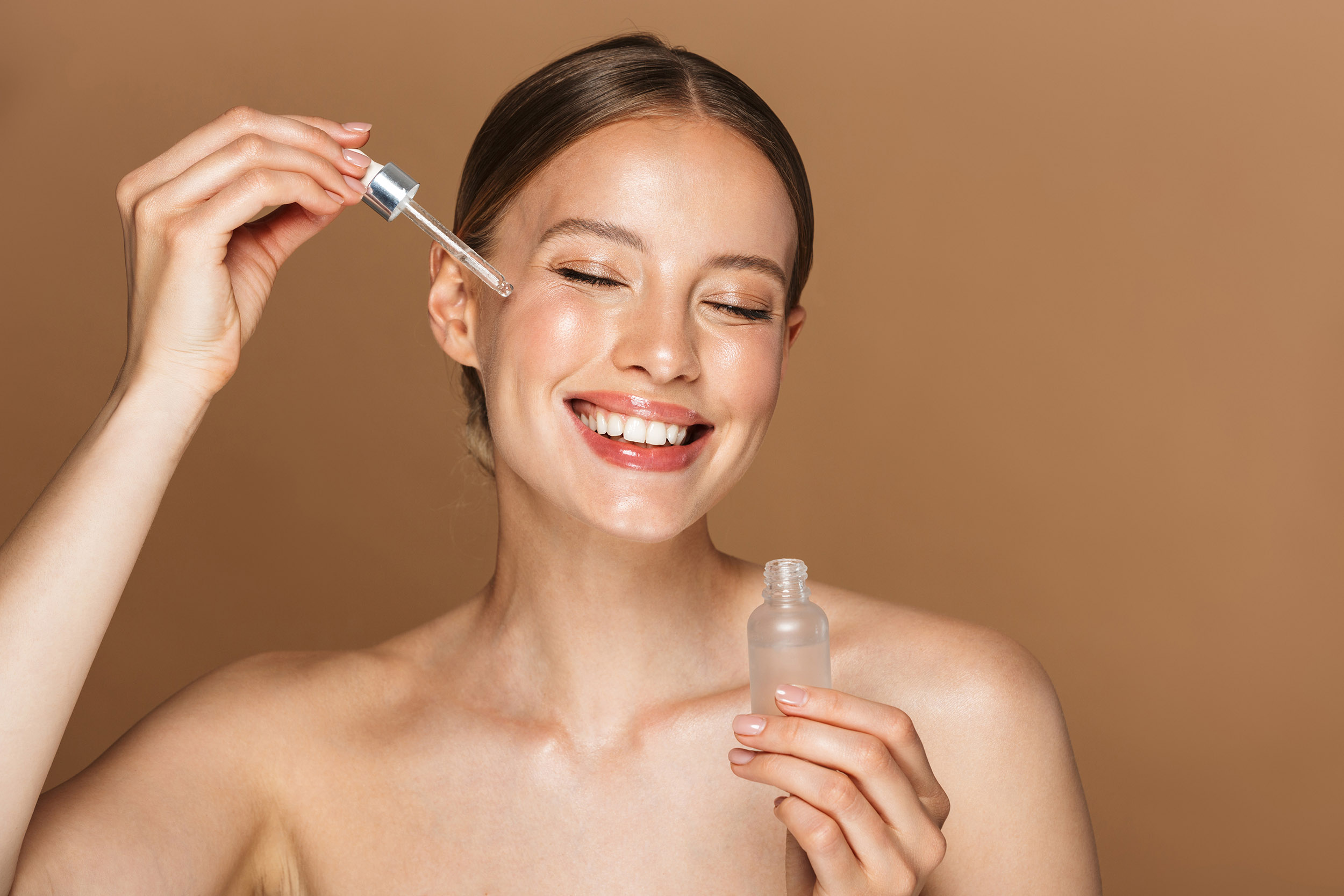 Woman using face oil serum on skin